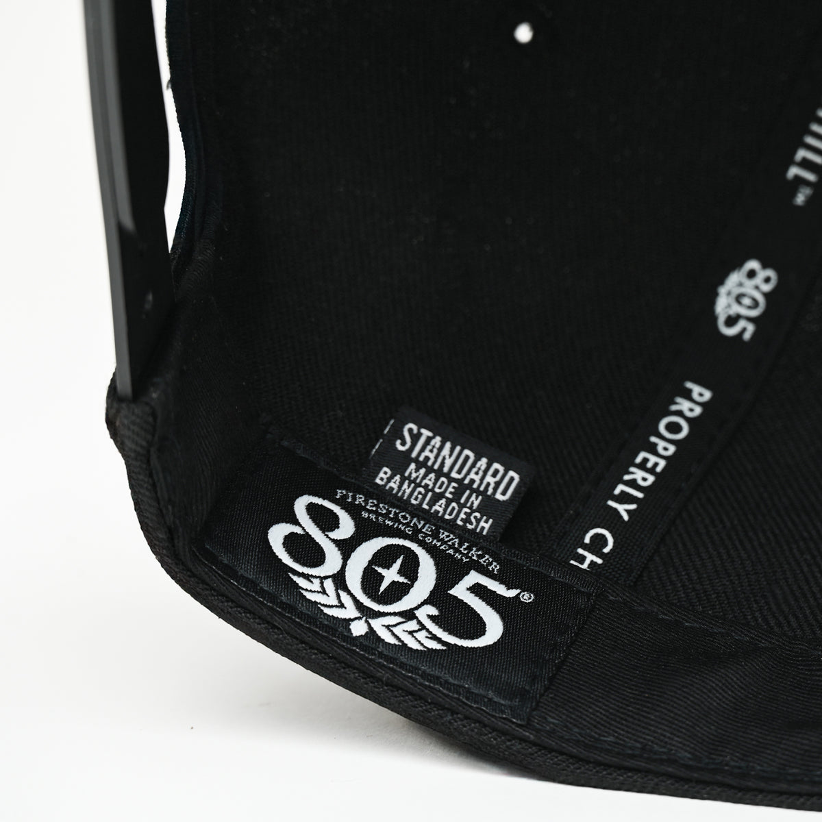 Interior close-up of 805 hat showing brand label and "Properly Chill" lining print, black