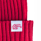Close-up of the white woven Cali Squeeze label on the cuff of the red Cali Squeeze Logo Beanie